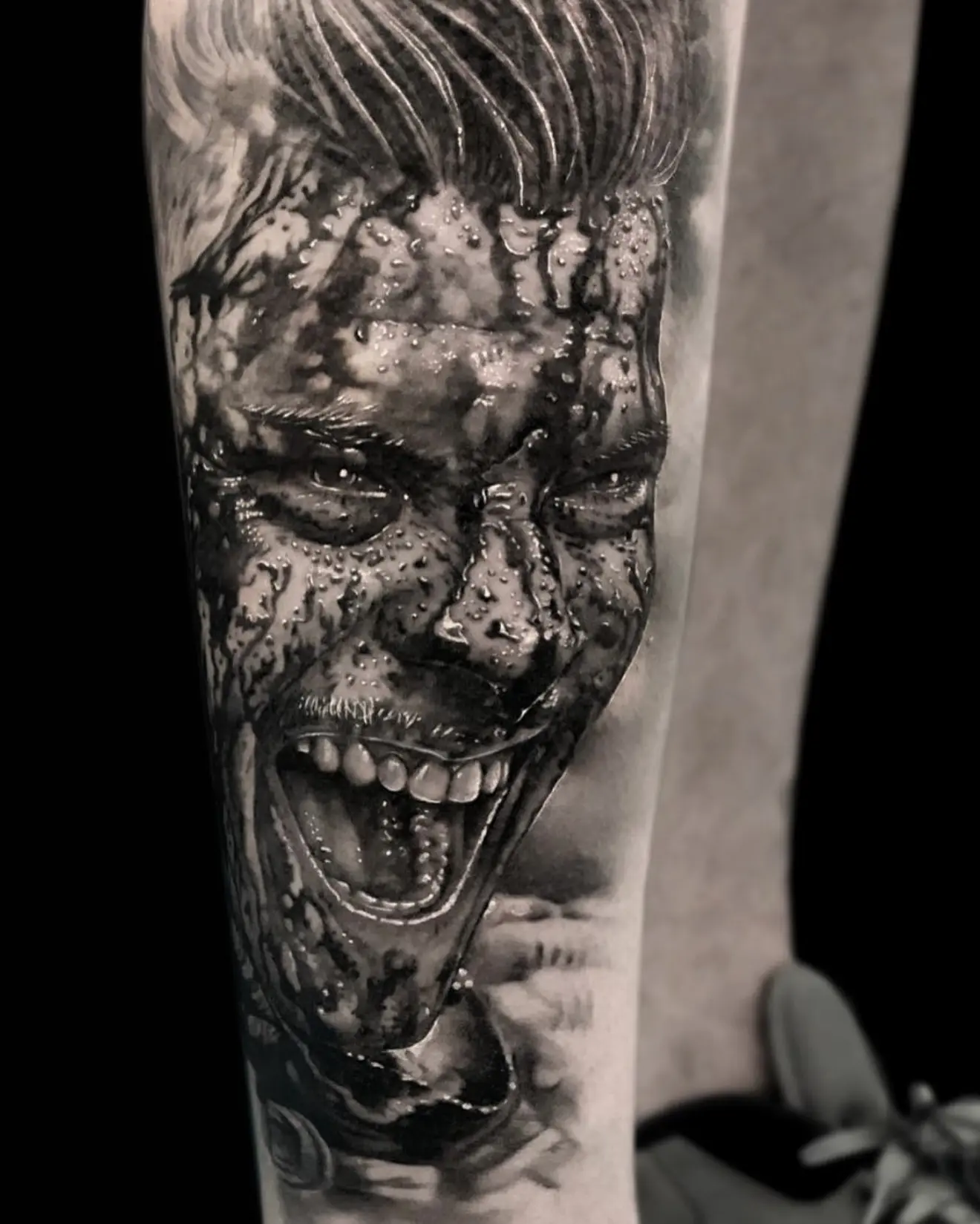 Tatuaje realista en black and grey del Joker mojado y sonriendo